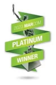 A stylized green and silver trophy with the text "2023 MARCOM PLATINUM WINNER" on ribbon-like banners.