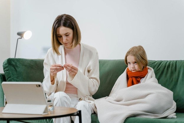 Mother is checking temperature of her child 