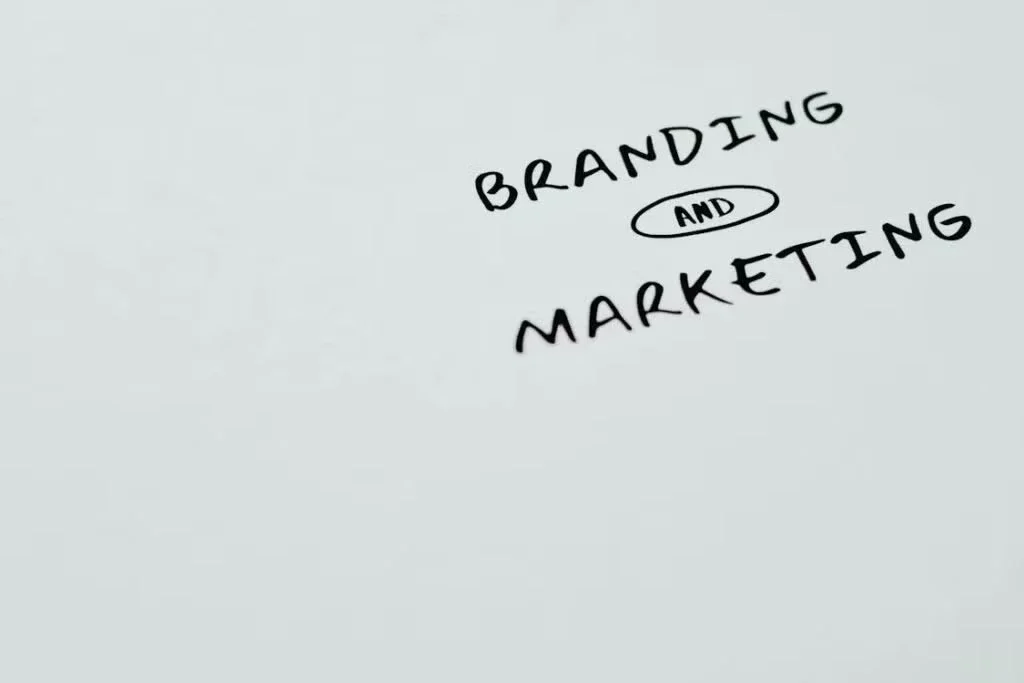 "Text 'BRANDING AND MARKETING' handwritten with a black marker on a white background."